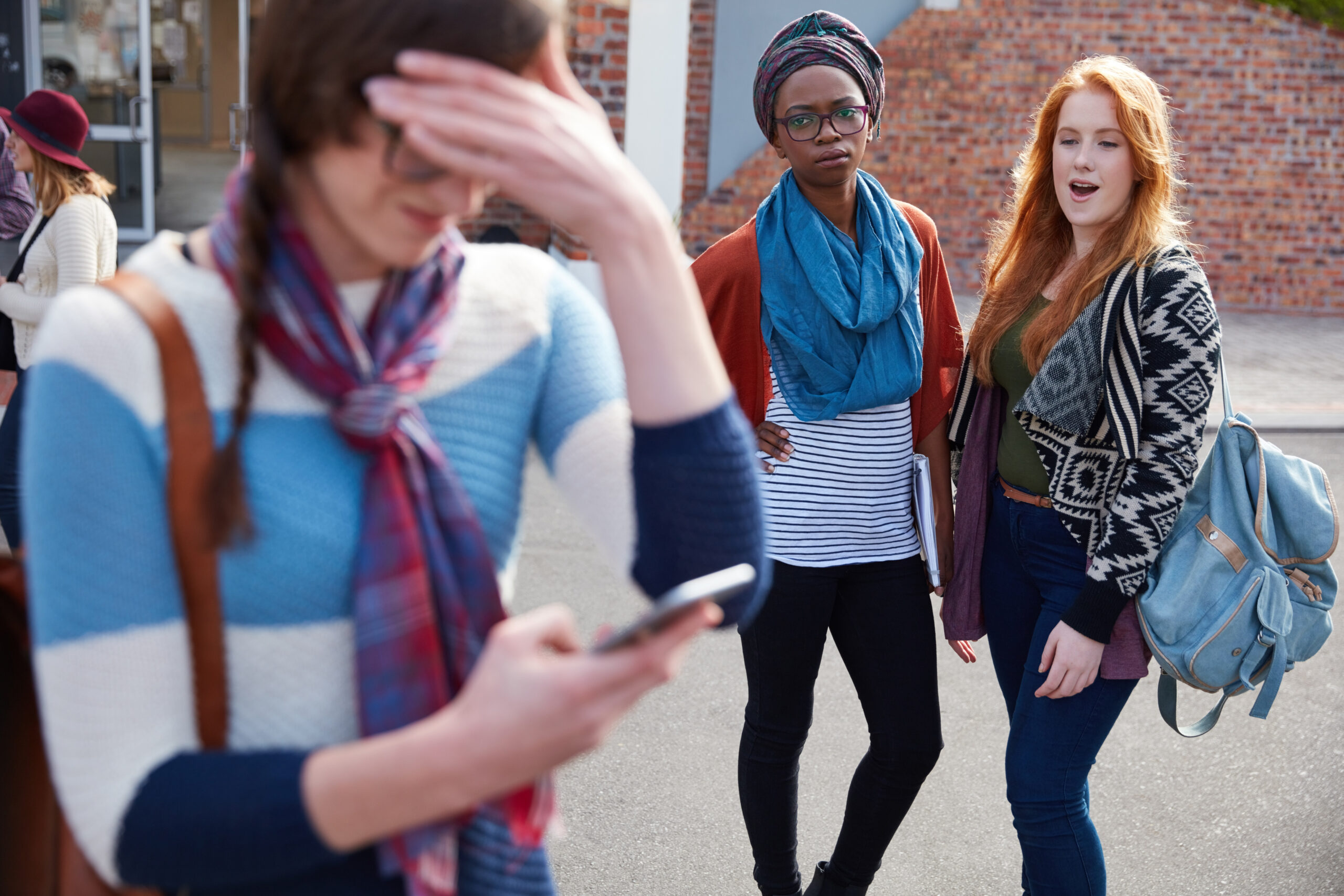 Addressing cyberbullying. Student with a phone and her head down.
